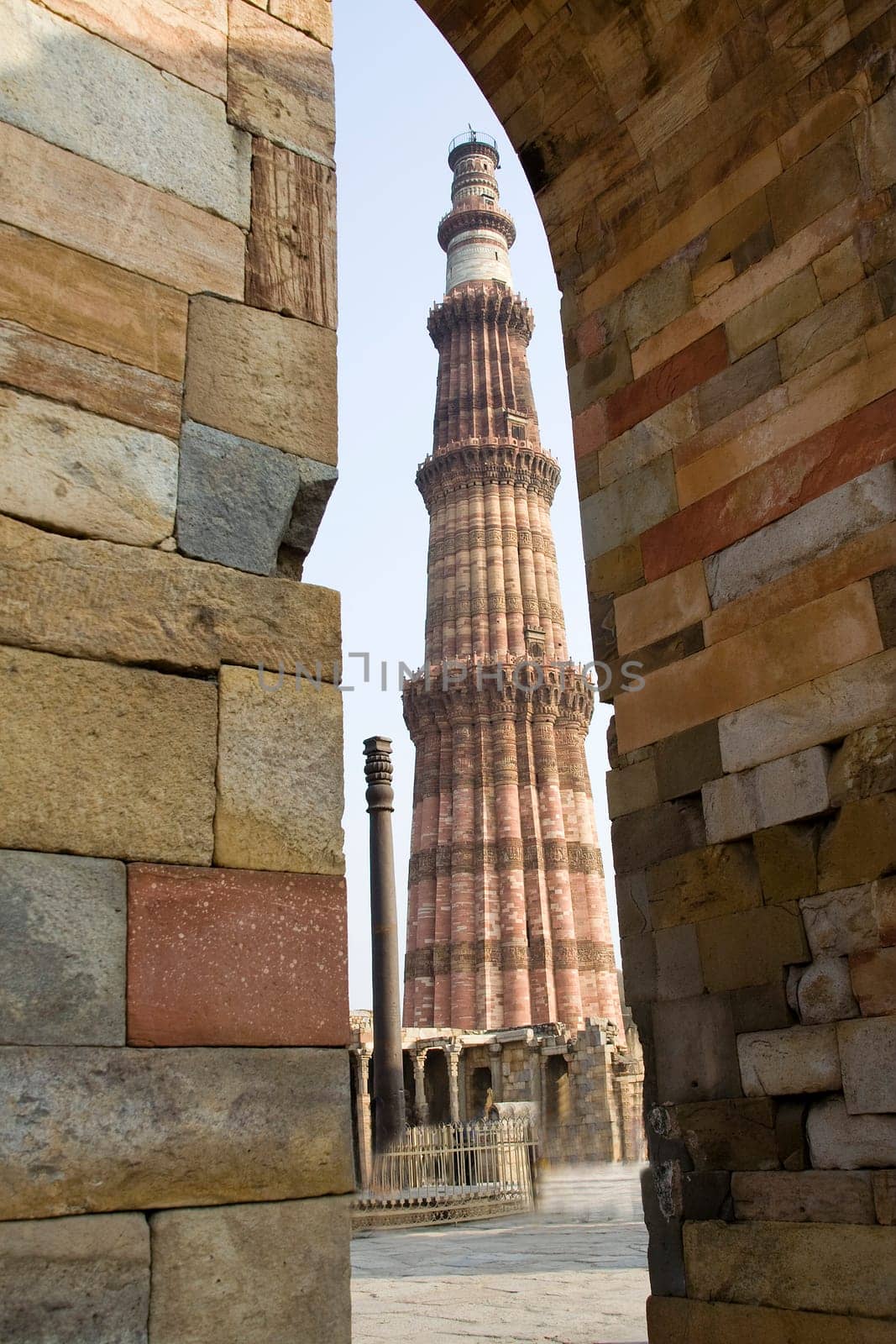 Qutub Minar and Iron Pillar viewed though stone wall corner and arch, Delhi, India, Asia