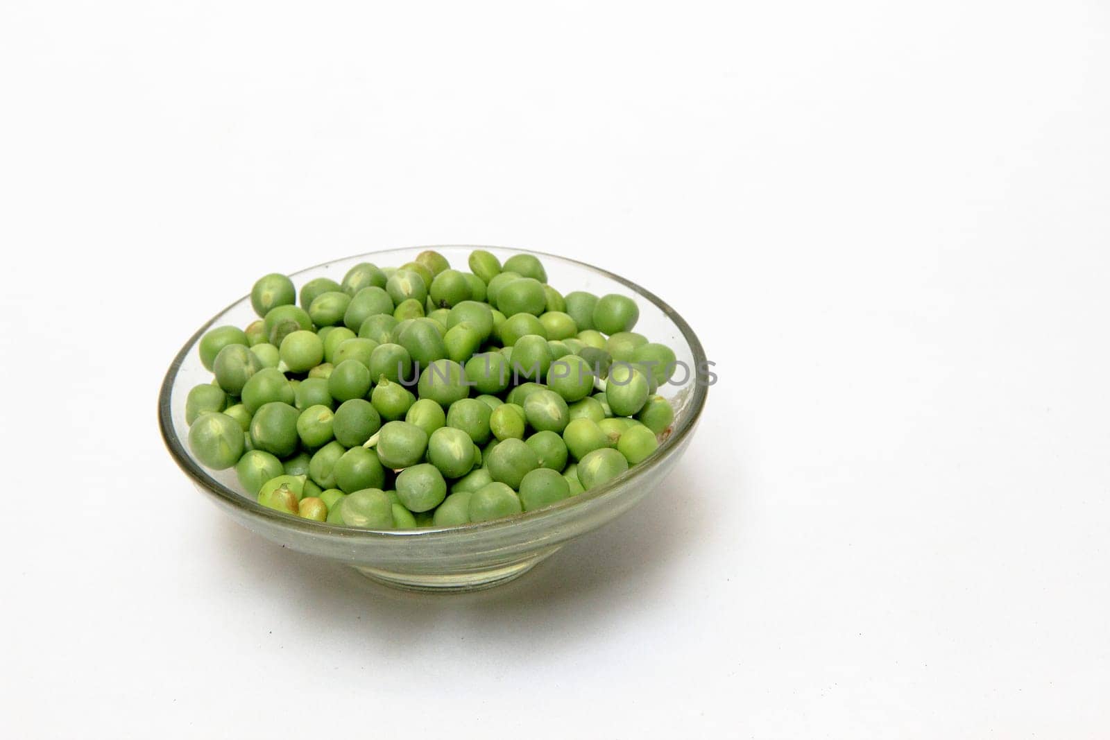 Glass dish containing fresh green peas, isolated on white