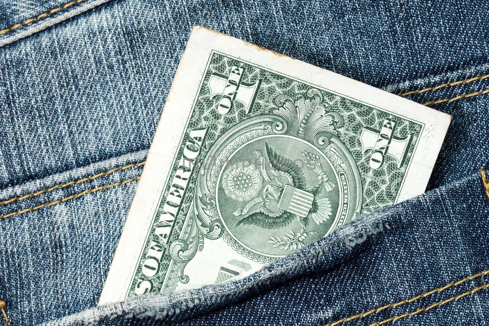 One dollar note in the back pocket of denim trousers