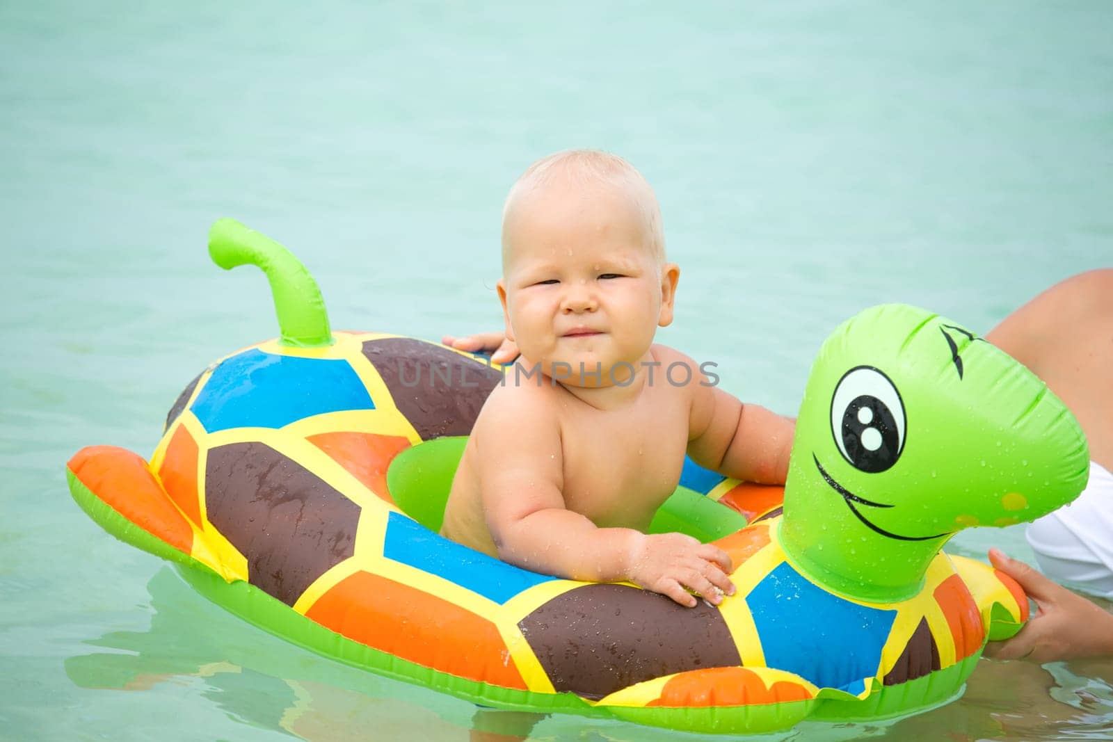 Baby bathing in the sea with swim ring