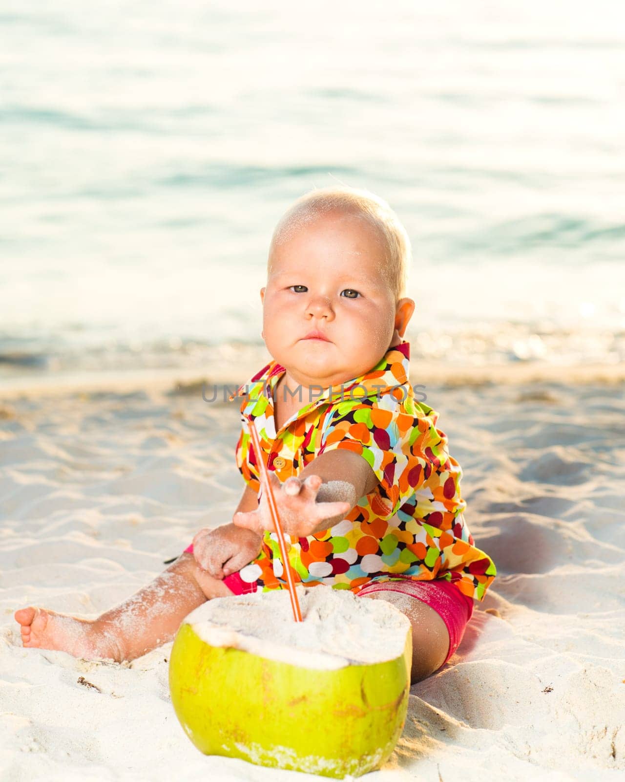 Funny baby with coconut on the beach