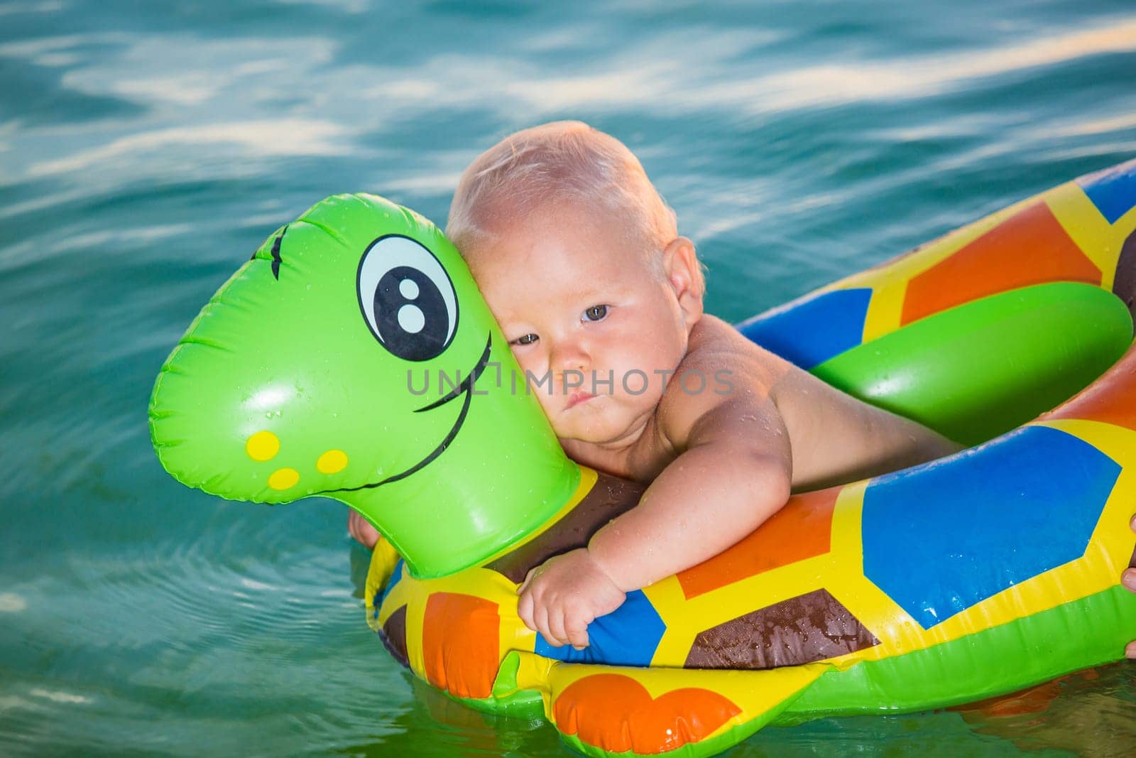 Baby bathing in the sea with swim ring