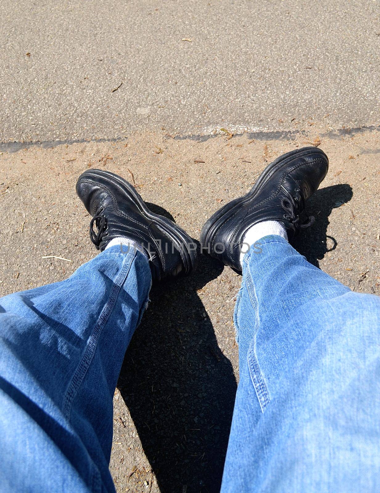 The legs of a tired hiker sitting on a bench, resting from his walk..