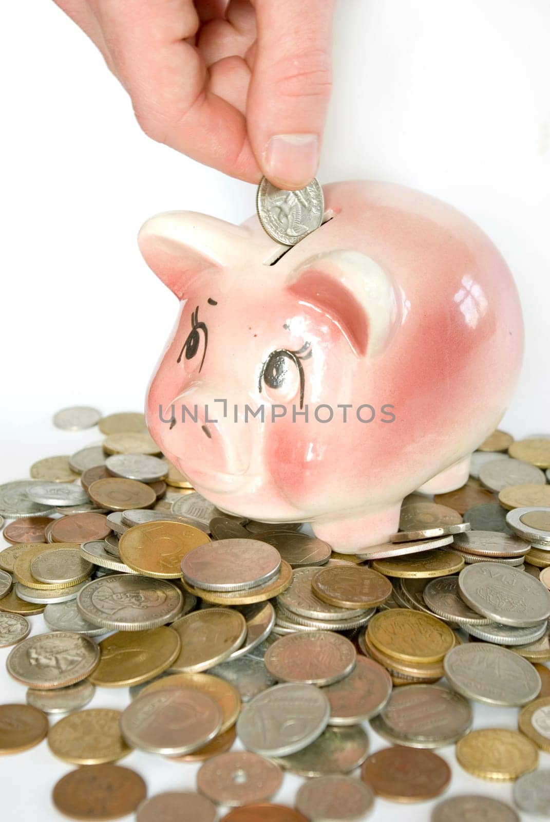 Hand inserting coin into piggy bank isolated on white