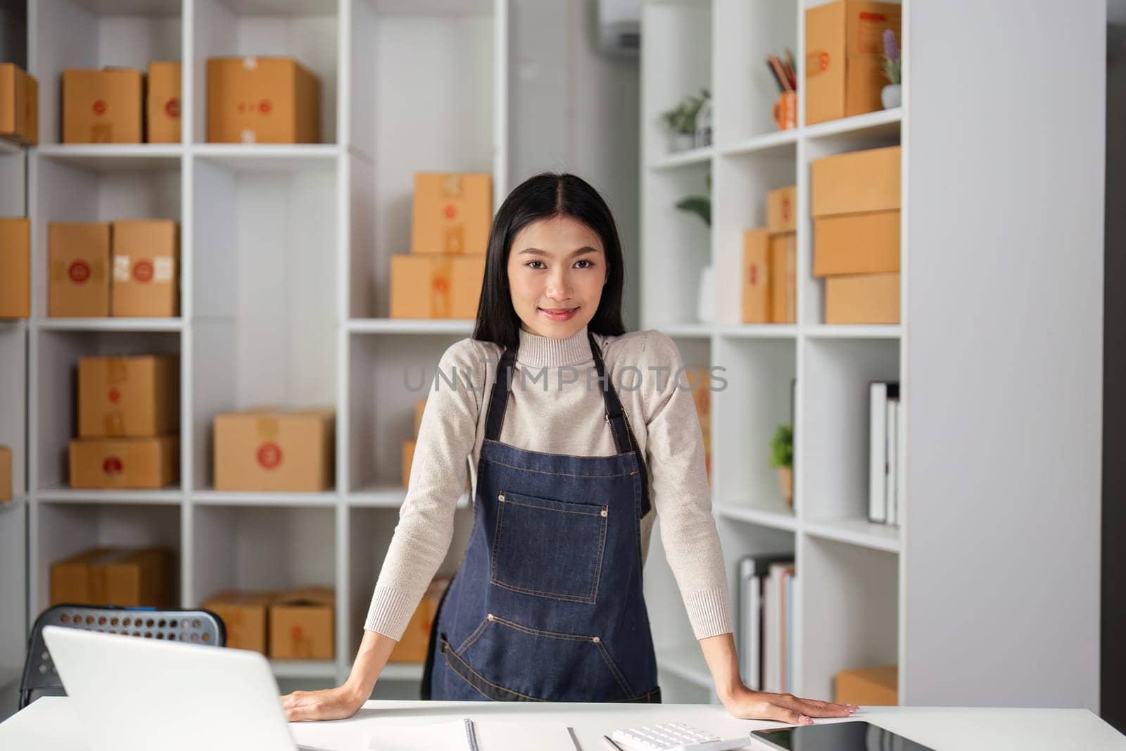 A confident young woman stands in a modern office with arms crossed, representing her entrepreneurial journey and dedication to success.