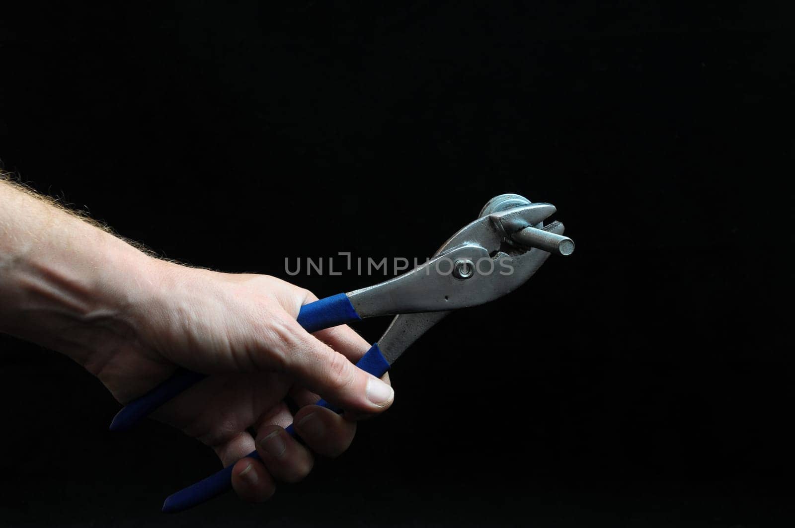 Pliers and a Hand on a Black Background