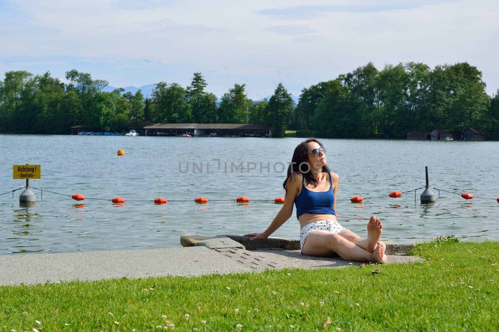Young woman tanning in front of a lake