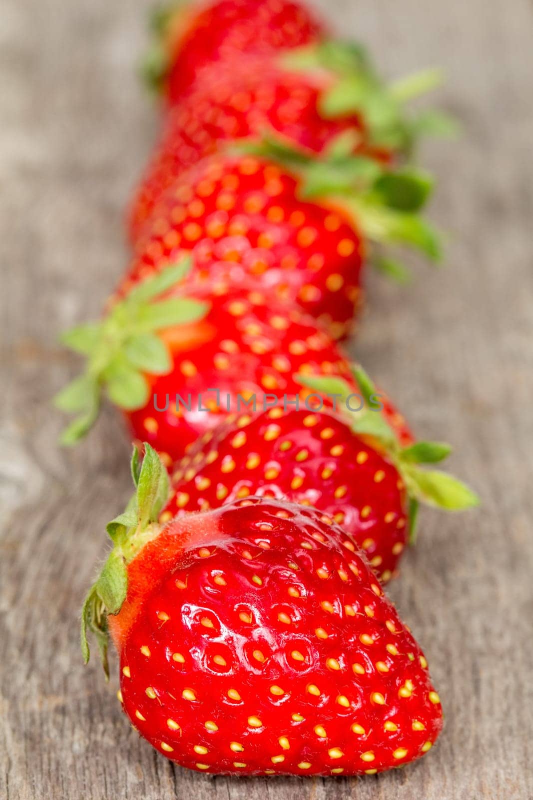 Ripe strawberries in a row on wooden background