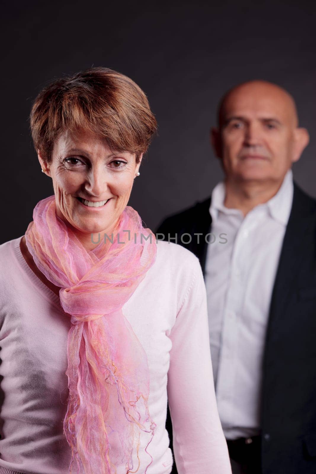 an old woman in foreground and an old man in background looking at her with concerns about her