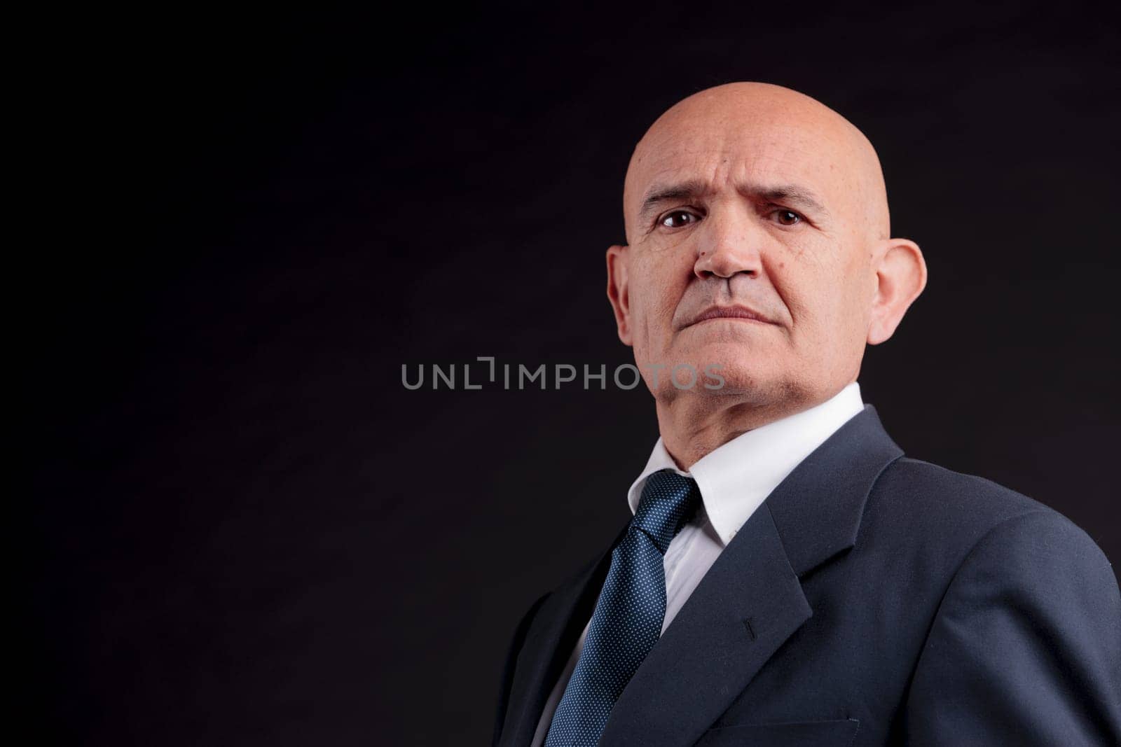 old bald self-confident businessman on a dark background