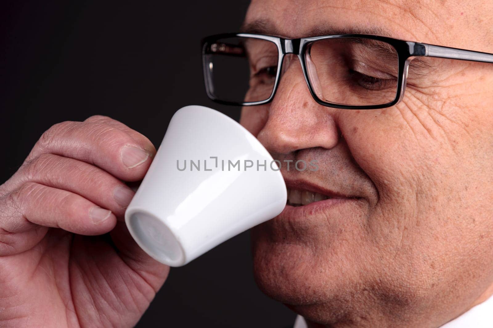 bald old smiling businessman holding a cup of espresso italian coffee