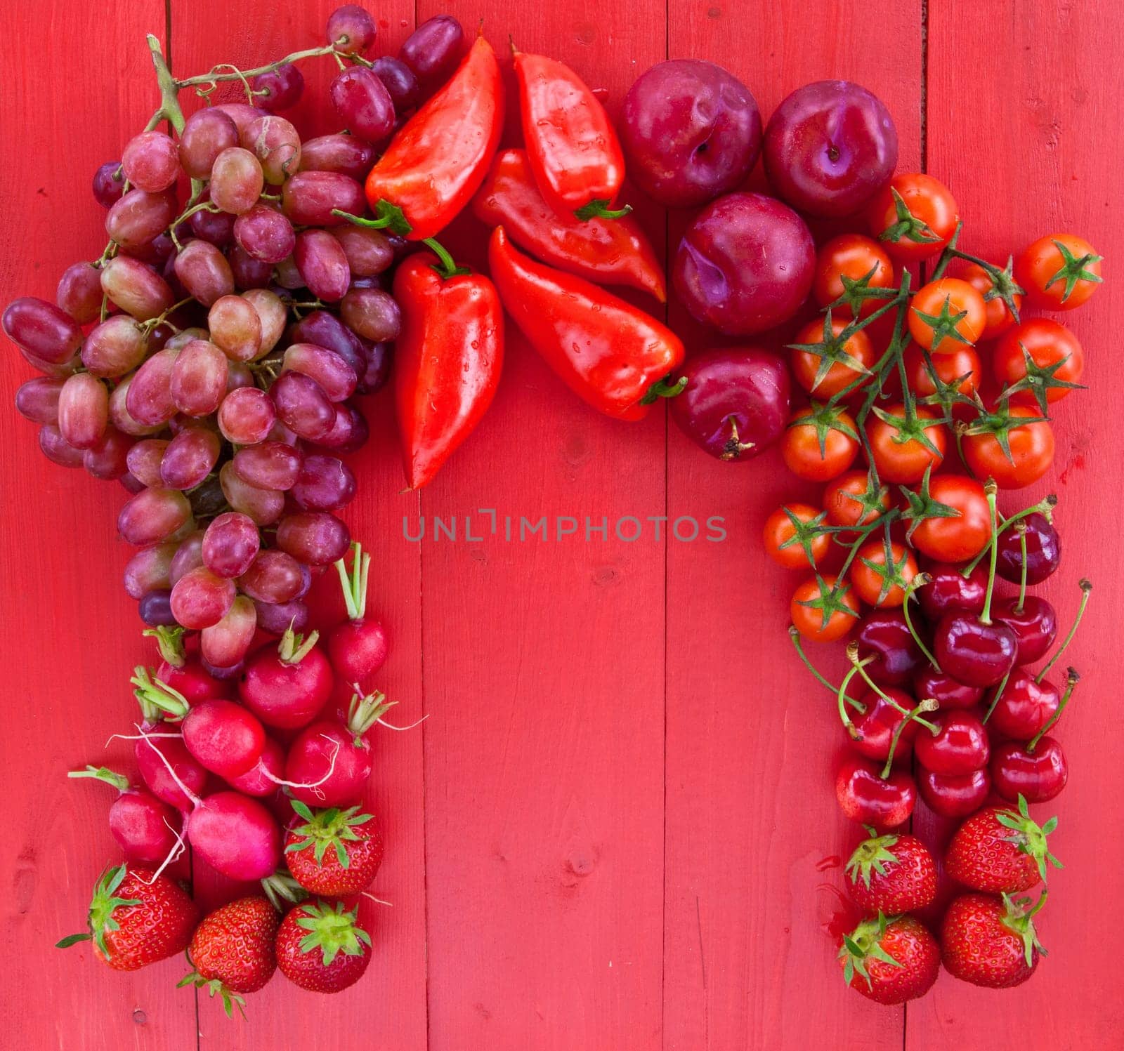 Fresh red fruits and vegetables on a red background