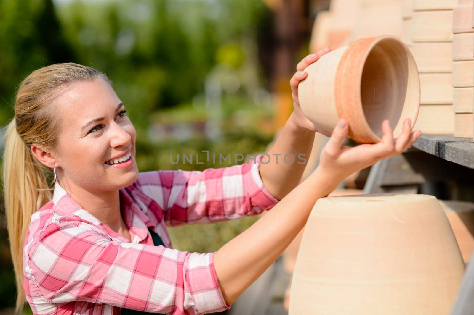 Garden center woman worker putting clay pots on shelf smiling
