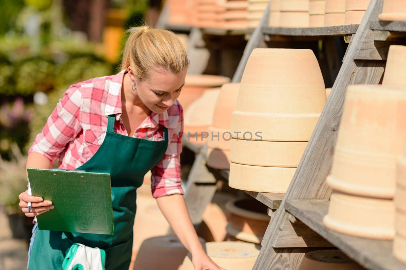 Garden center woman looking down at clay pots sunny day