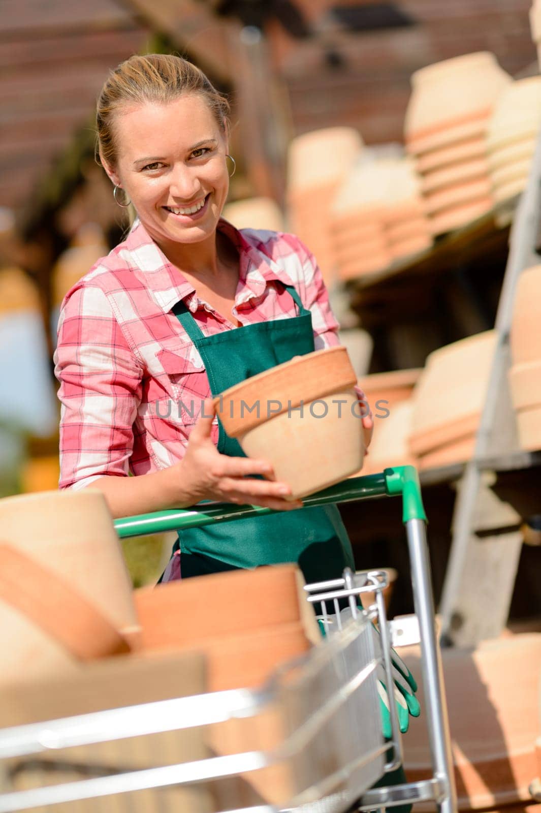 Garden center woman worker putting clay pots on shopping cart
