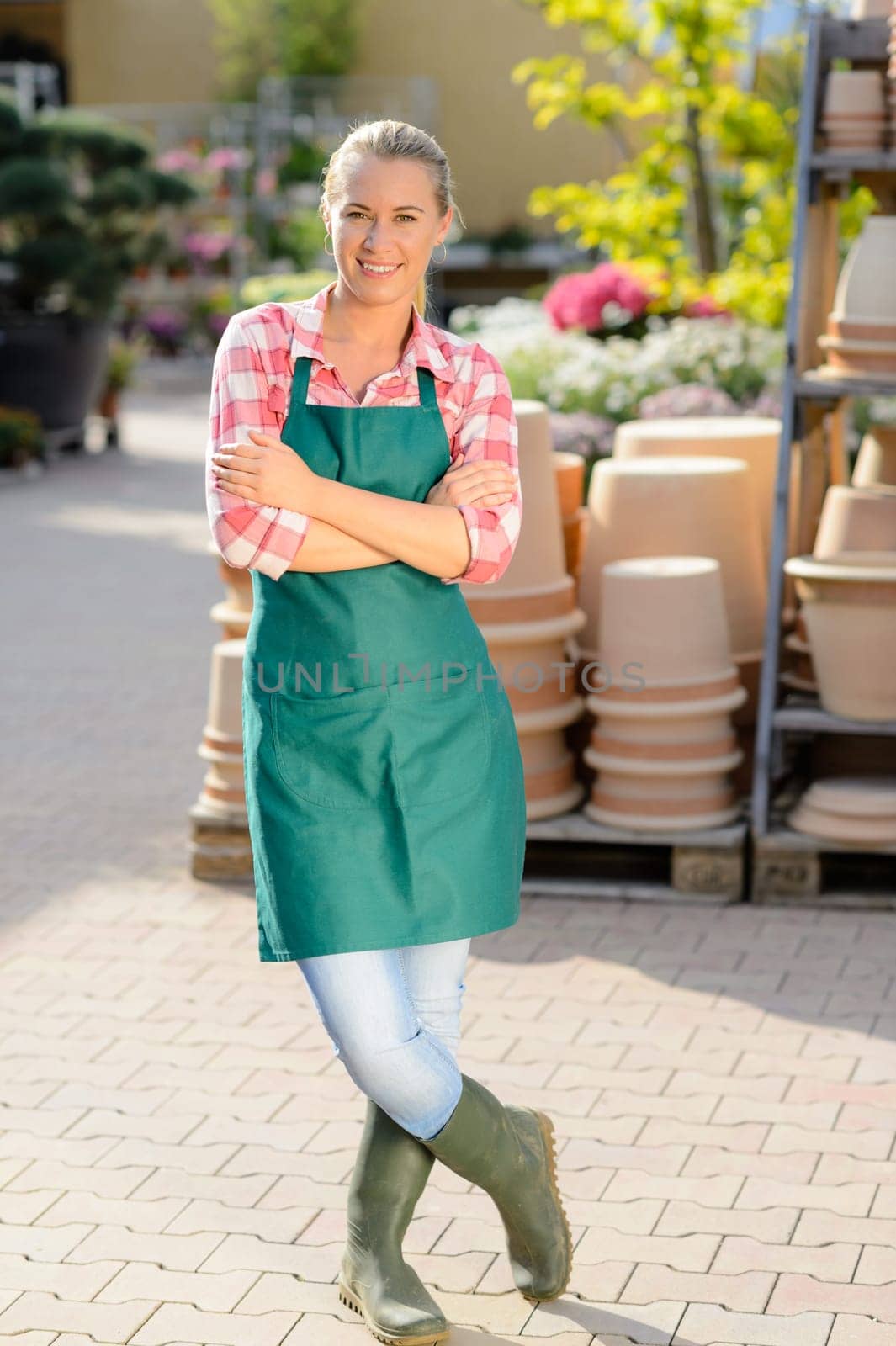 Garden center woman worker with apron standing with arms crossed
