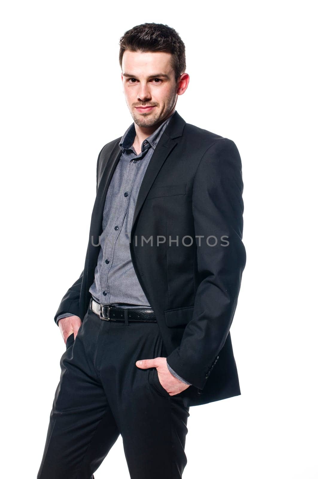 young businessman in a suit is standing casually with hands in pocket. Isolated on white