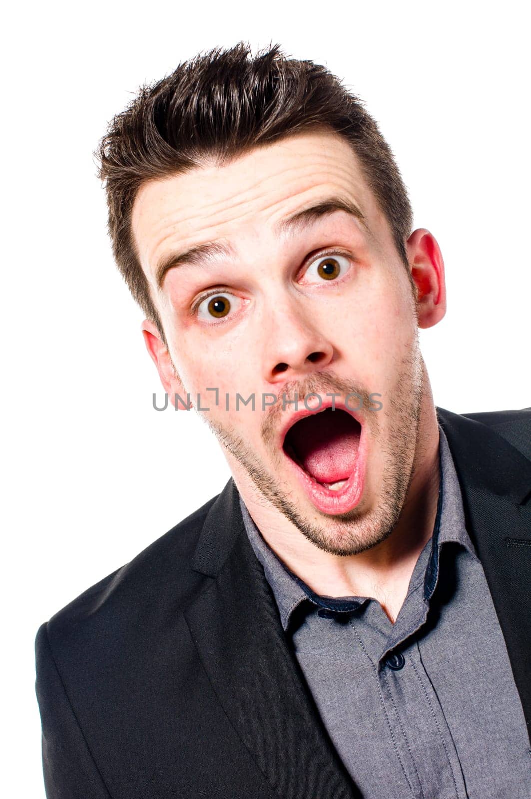 young businessman in a suit looking shocked and surprised with open mouth at the camera. Isolated on white.