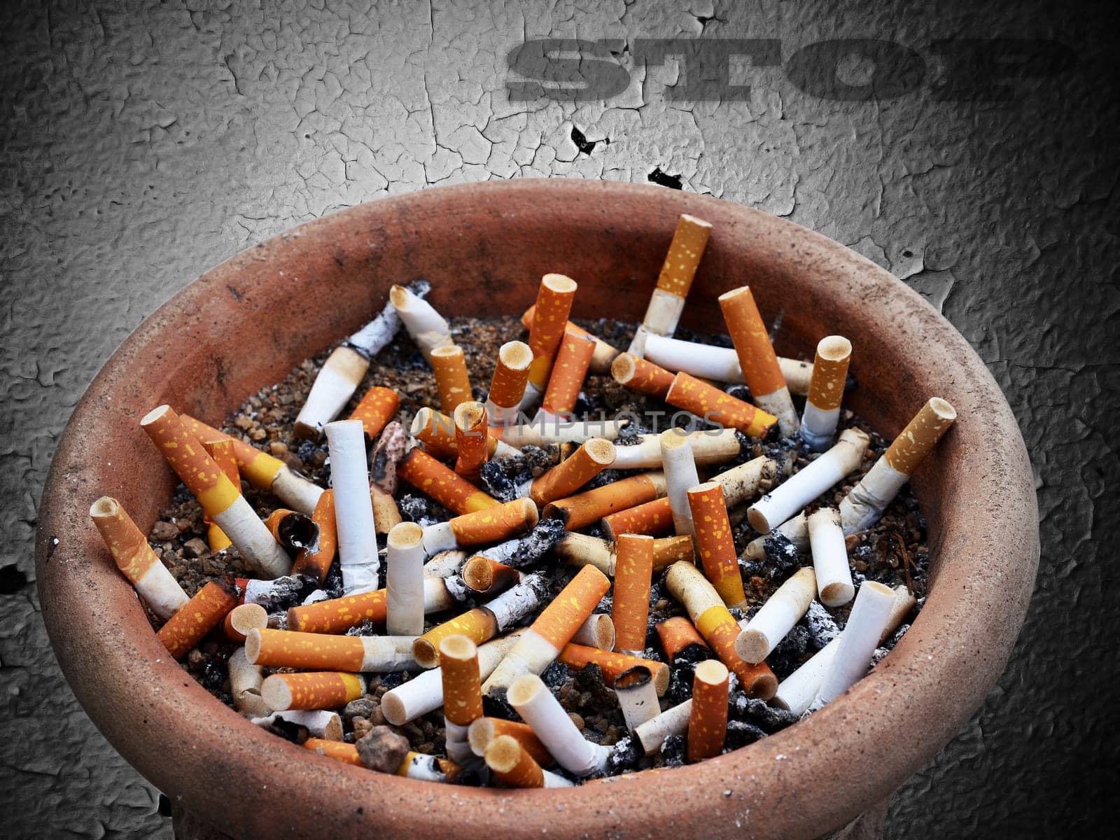 Cigarette addiction in ashtray on old wall  background