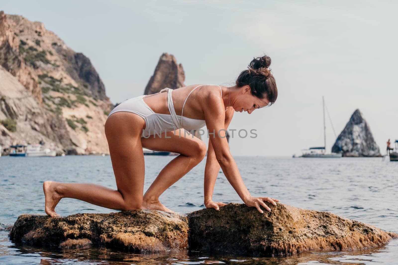 Woman sea yoga. Happy women meditating in yoga pose on the beach, ocean and rock mountains. Motivation and inspirational fit and exercising. Healthy lifestyle outdoors in nature, fitness concept. by panophotograph