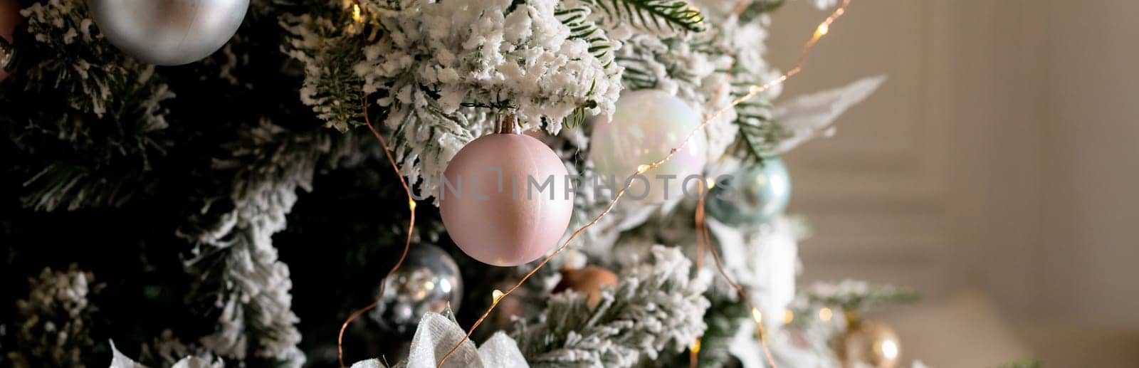 Artificial Christmas tree in a bright interior with silver flowers and snow on the branches. The concept of New year and Christmas