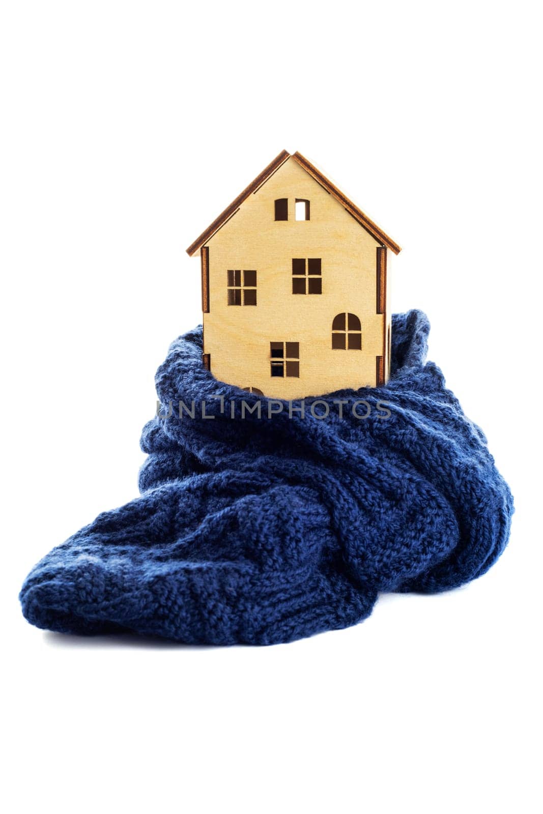 Wooden toy house is wrapped in a warm scarf isolated on white background. House insulation concept. Warm house concept