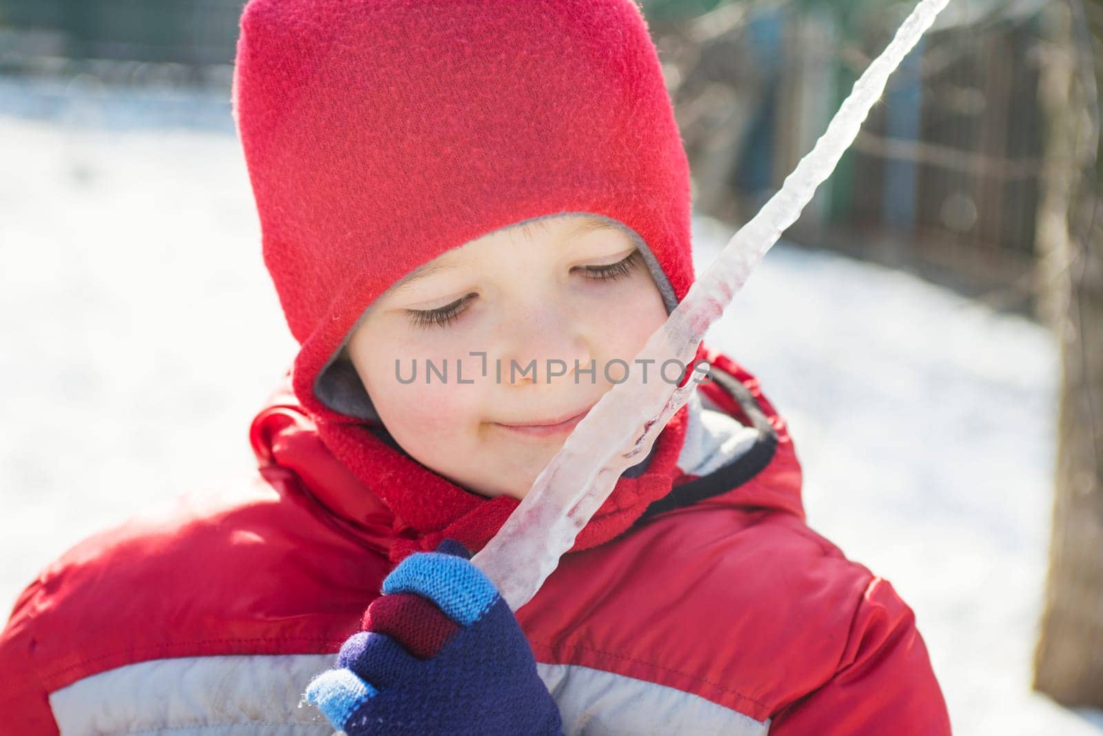 The little boy holds an icicle in her hands in the winter outdoors.