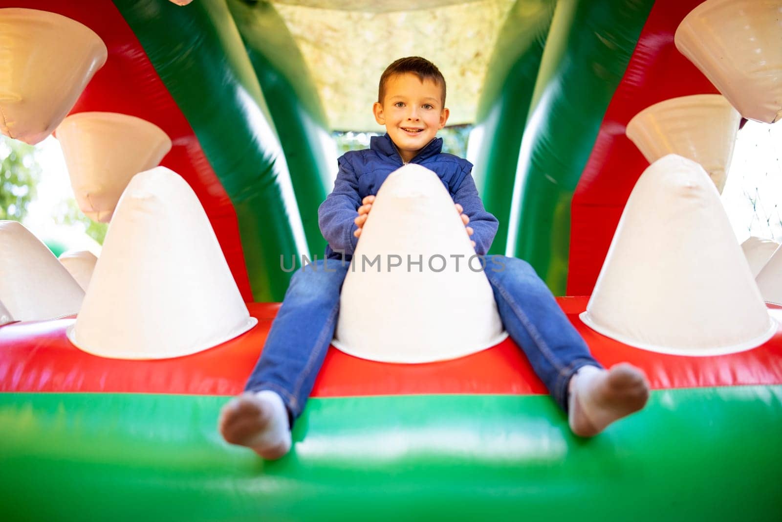 Happy kid having fun on colorful inflatable attraction playground. Child have fun and ride on the outdoor playground.