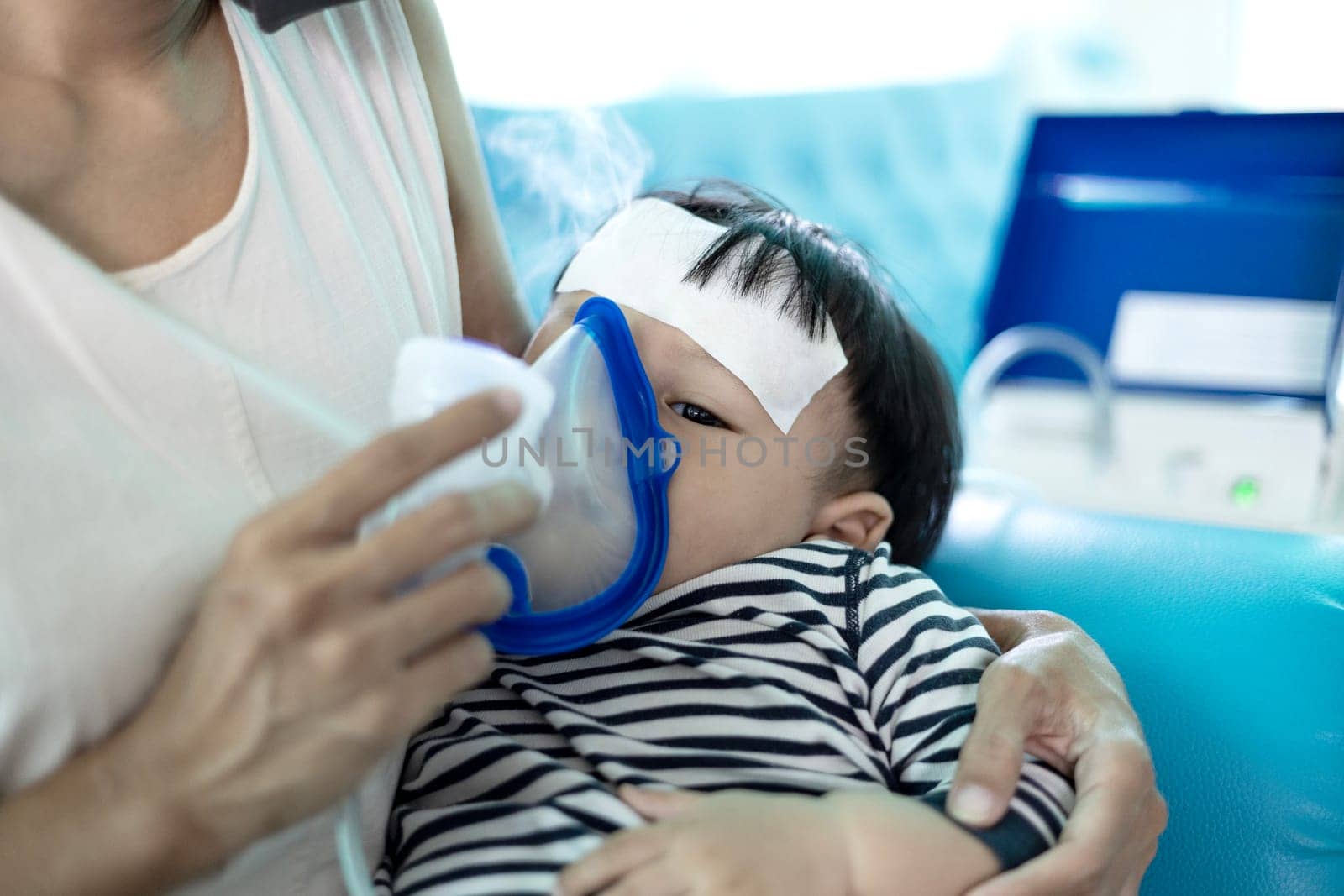 Little boy having inhalation for easing cough. Mother Helping Little Son Using Nebulizer During Inhalation.