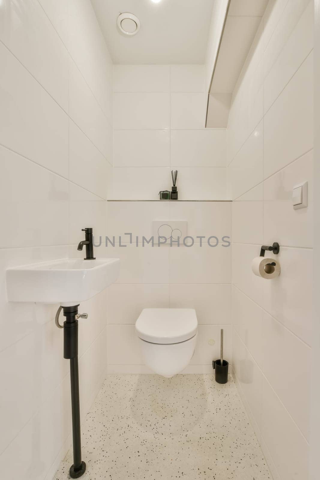 a white bathroom with black and white tiles on the floor, toilet in the fore - image taken from above
