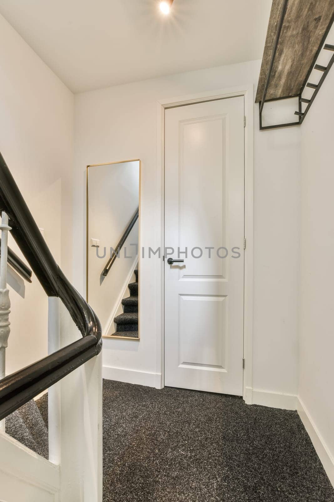 a white staircase with black carpeting and an open door leading to the second floor in a mirror is on the wall