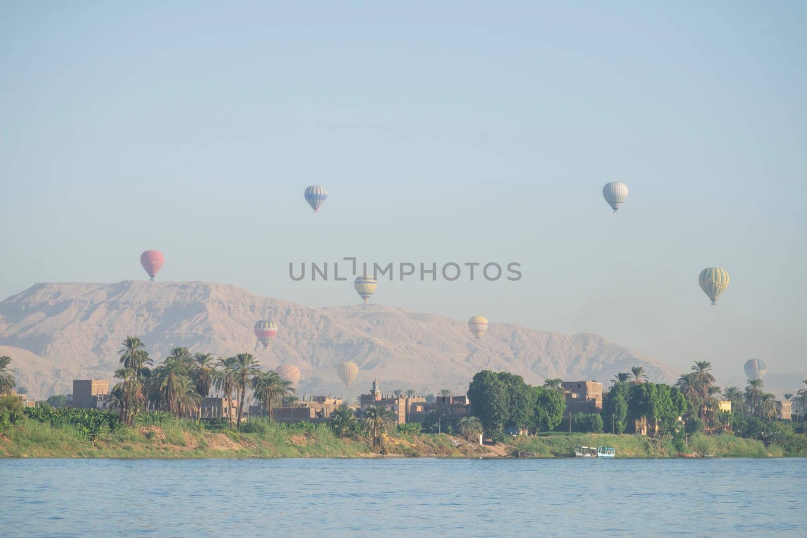Panoramic landscape view across nile river to luxor west bank with mountains and hot air balloons flying