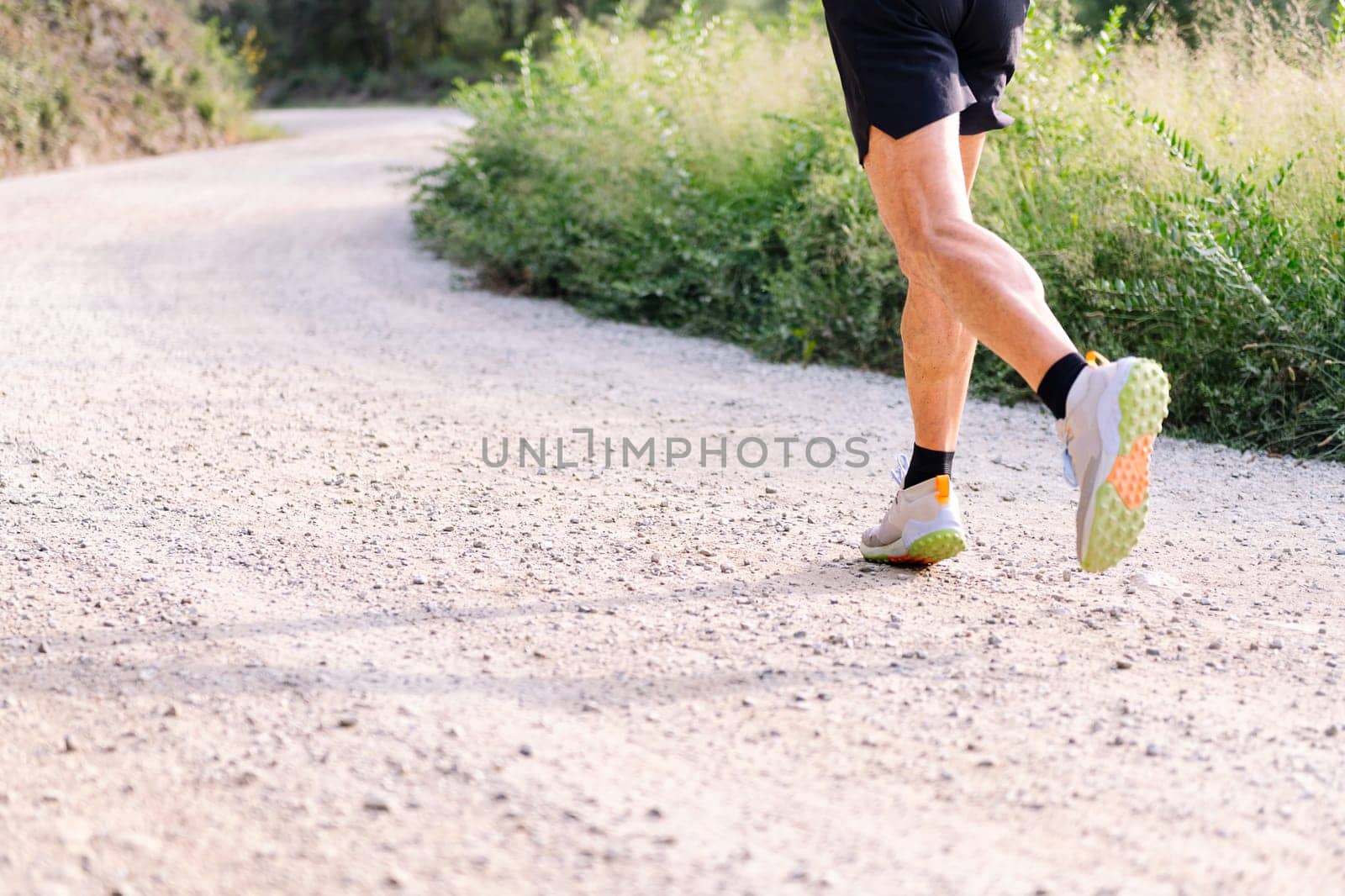 legs of an unrecognizable man running in the countryside, concept of sport in nature and active lifestyle, copy space for text