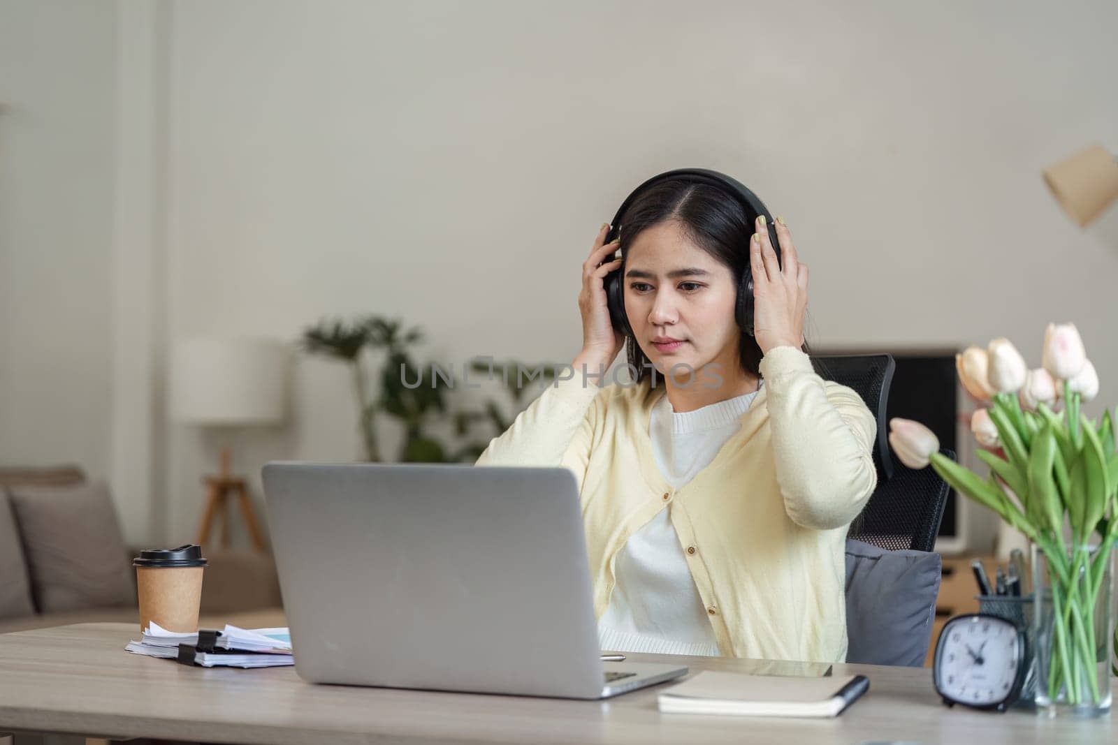 A dedicated freelance businesswoman works from home, wearing headphones and engaged with her laptop, showcasing modern remote work.