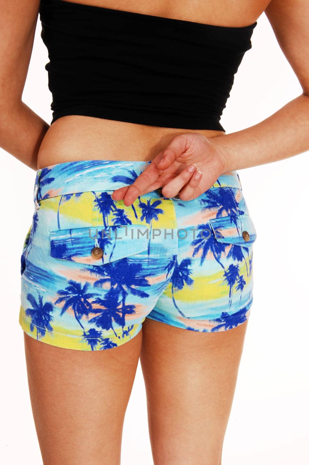 A closeup picture of the back and butt of a young woman in shorts with.her crossed finger, isolated on white background..