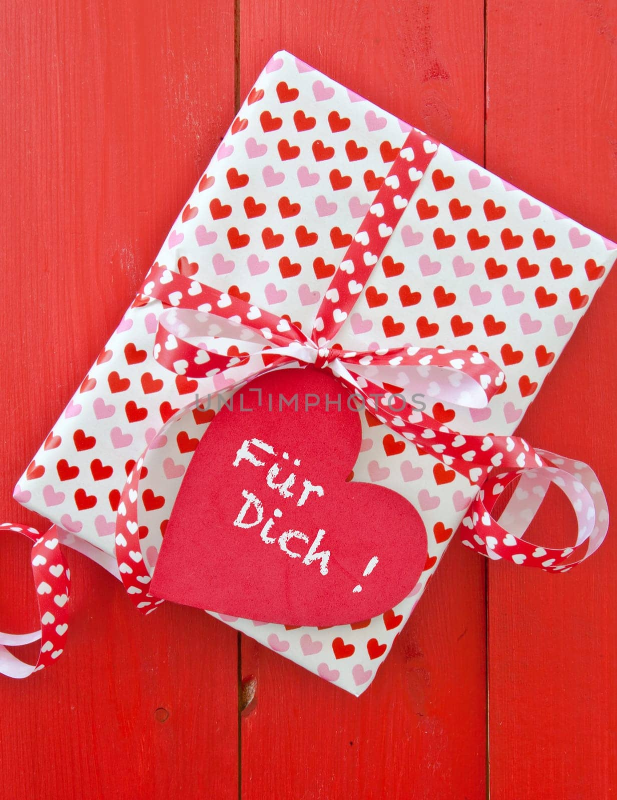 Small gift with hearts and bow on red