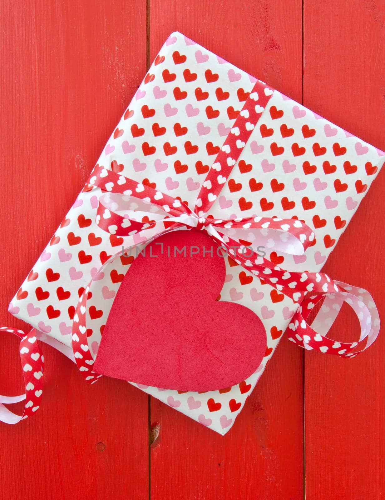 Small gift with hearts and bow on red