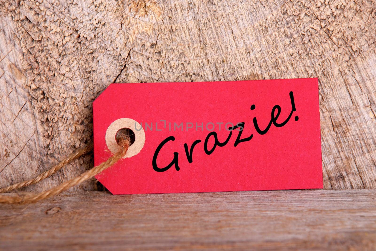 A Red Tag on Wood with the Italian Word Grazie which means Thanks