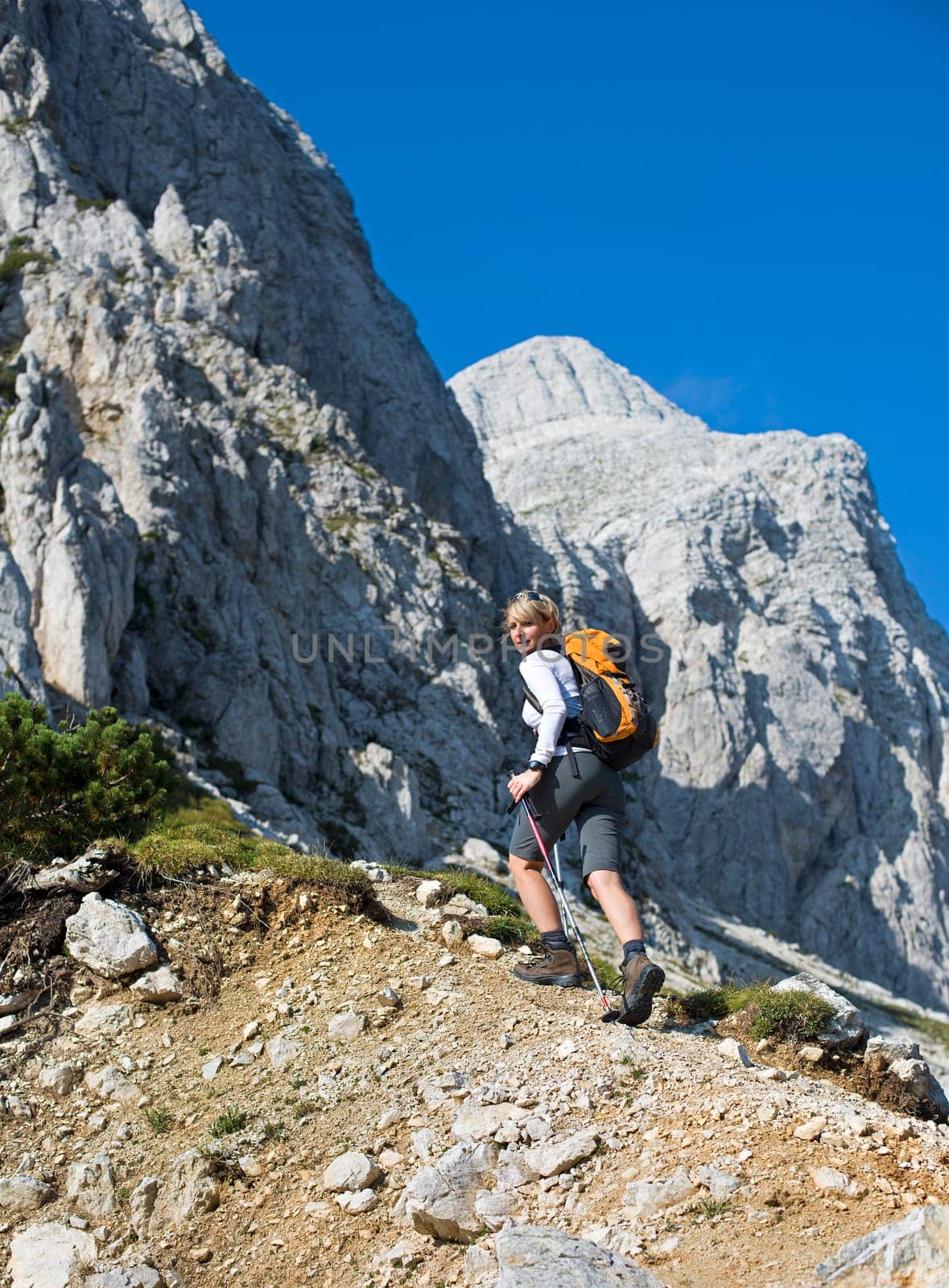 Young woman on a sunny day hiking in high mountains