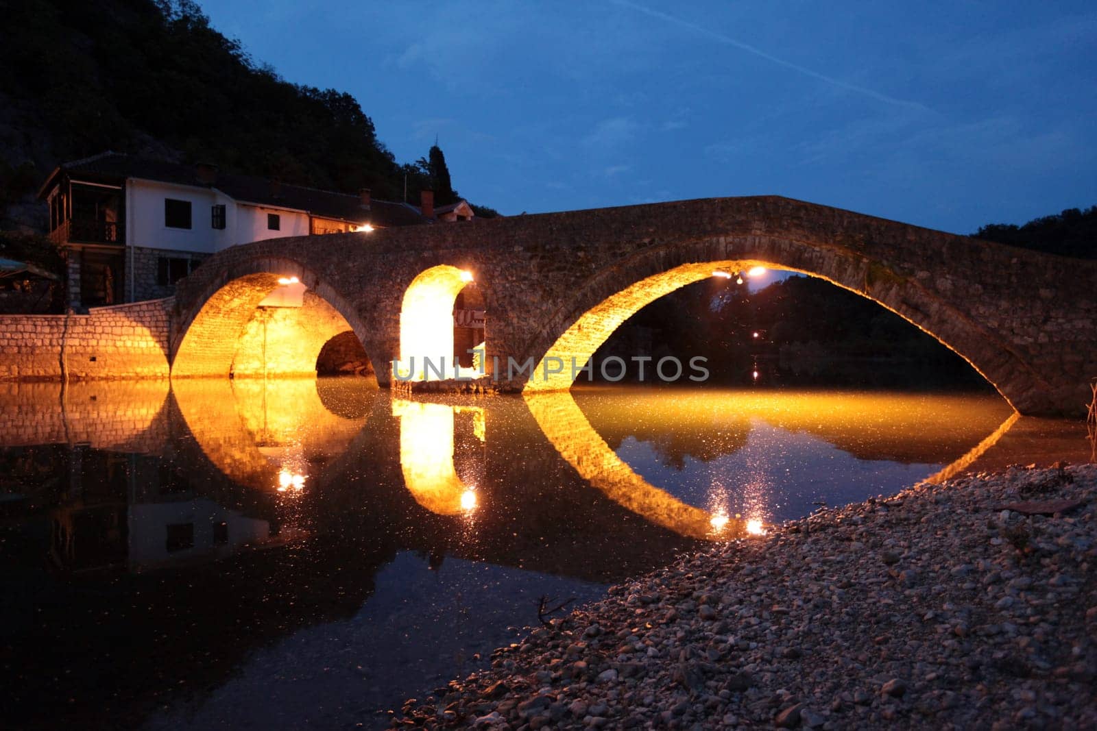 The landscape with the stone bridge of Rijeka Crnojevica with the river Rijeka Crnojevica at the western end of the Skadarsko Jezero lake or Skadar lake in Central Montenegro in Montenegro in the Balkans on the Mediterranean Sea in Europe.