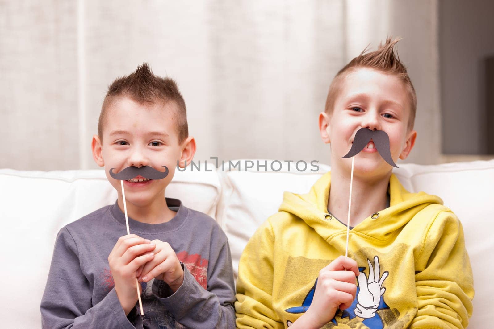 two kids making funny faces with fake moustaches