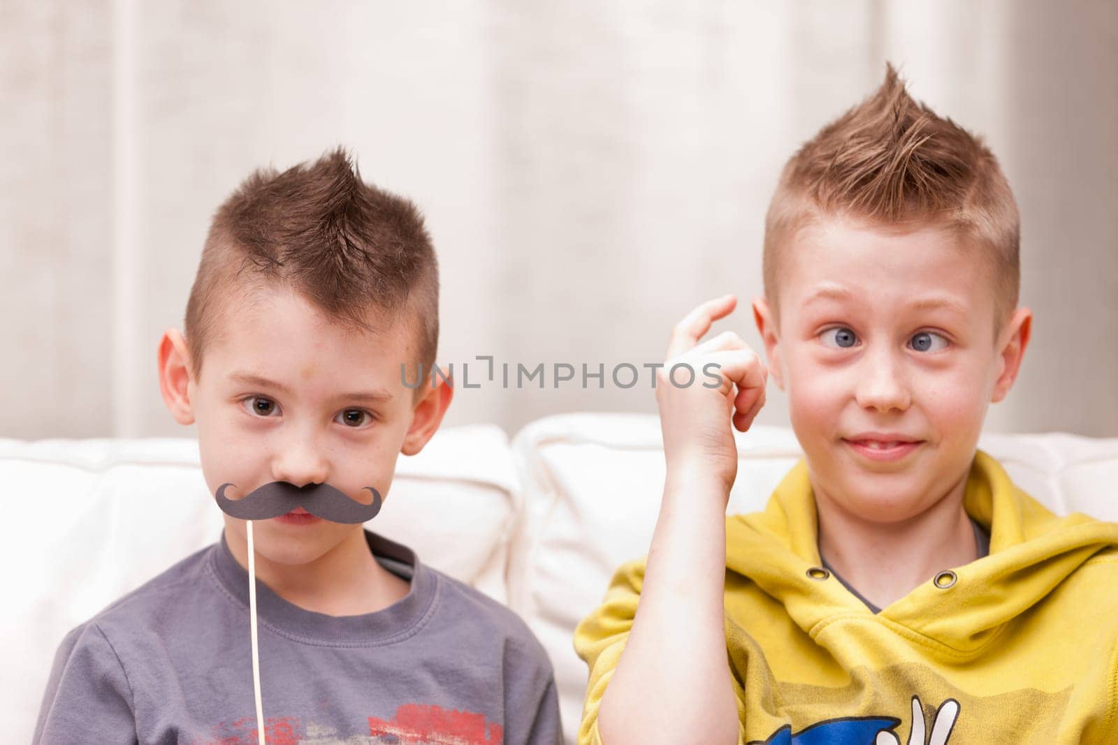 two kids making funny faces with fake moustaches