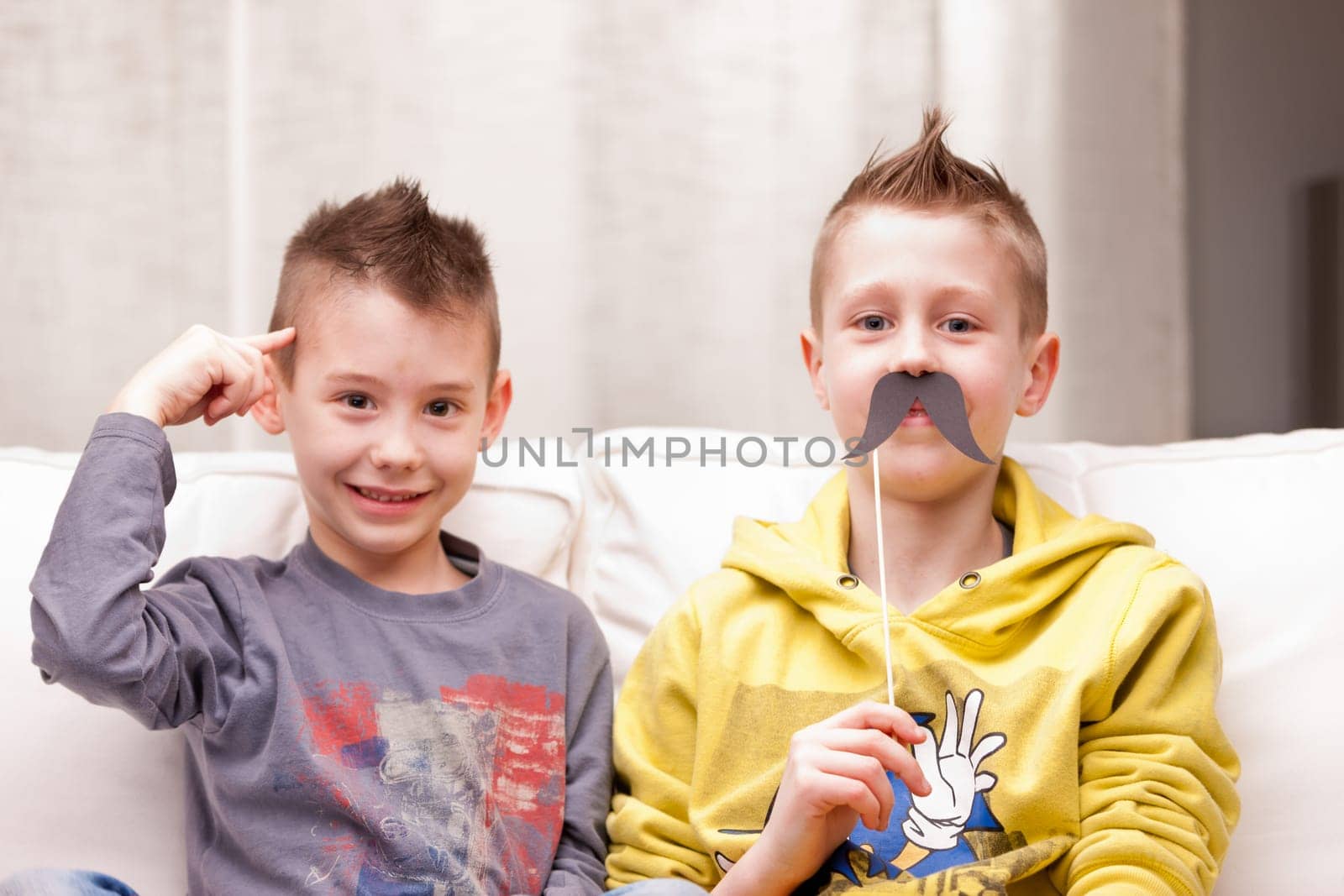 two kids making funny faces with fake moustaches