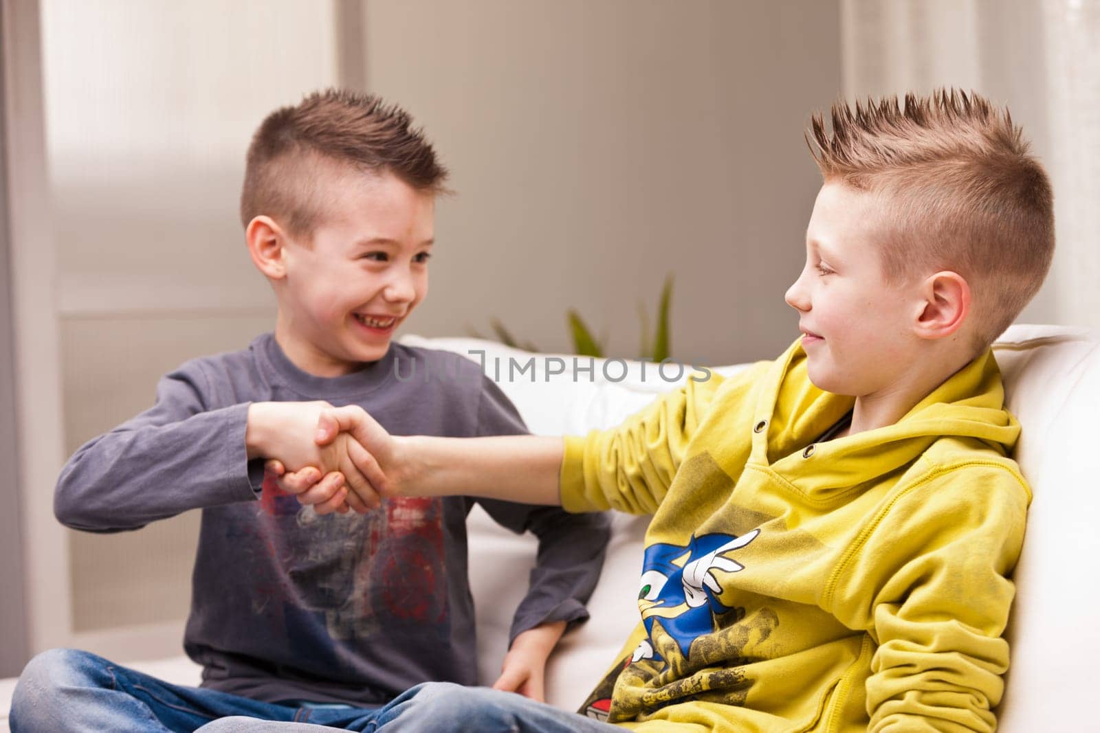 two little boys handshaking with a smile