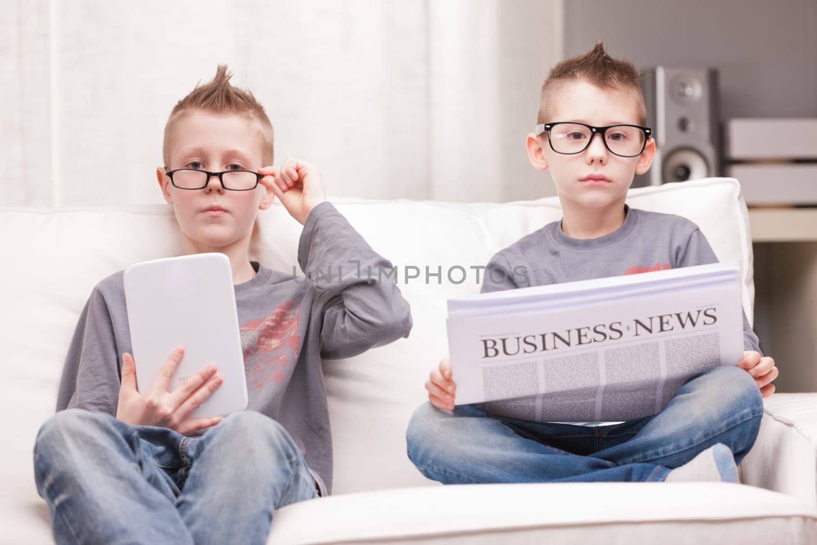 two little boys reading on newspapers or digital devices
