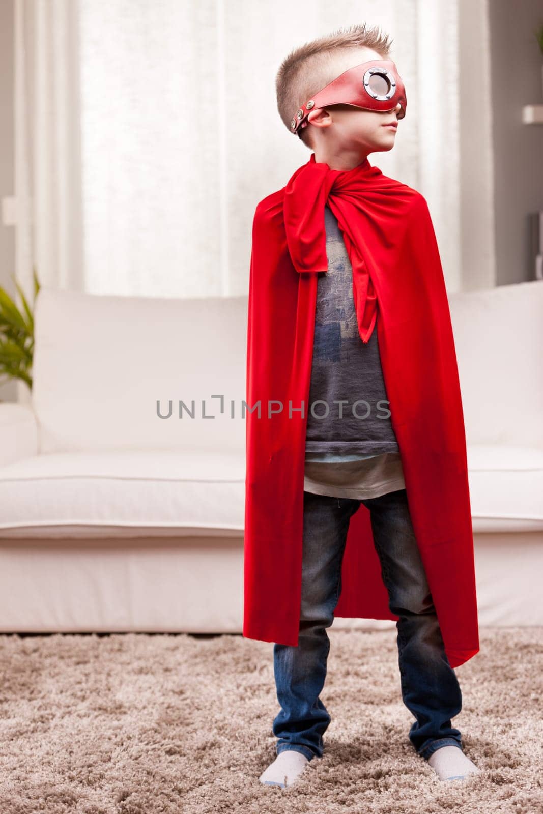 a little kid playing as a red cloak serious superhero