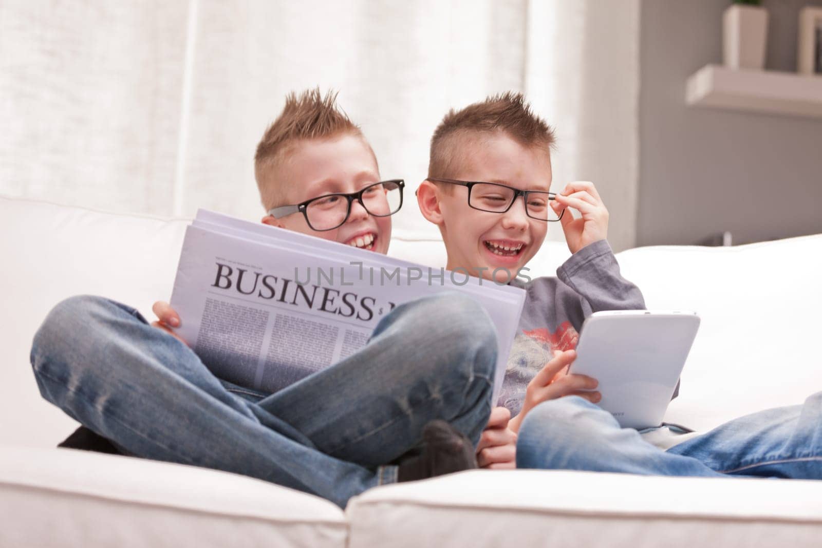 two little boys reading on newspapers or digital devices