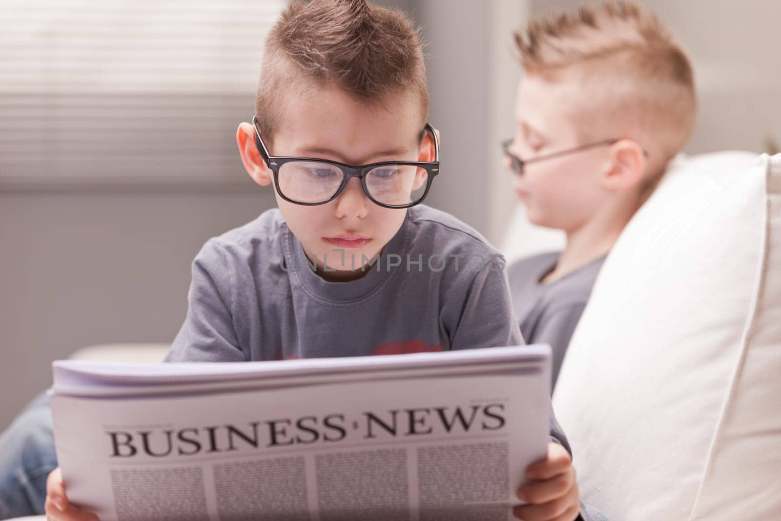 two little boys reading on newspapers or digital devices