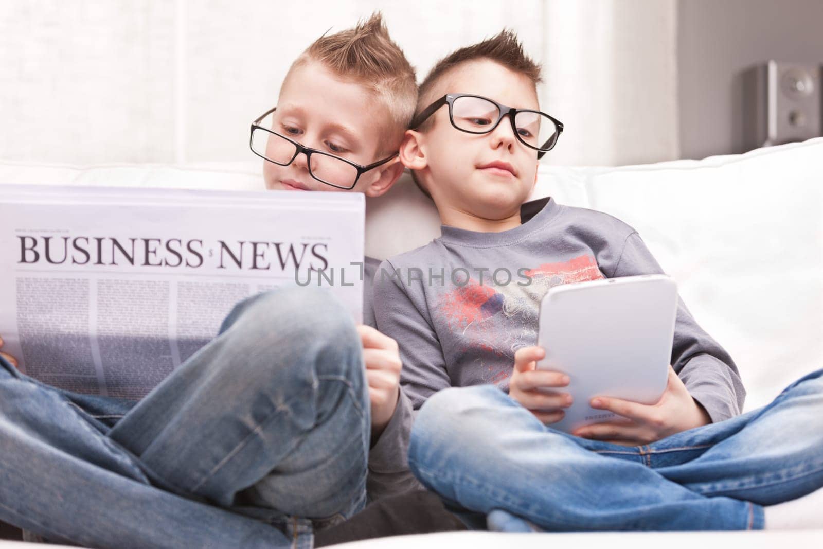 two little boys reading on newspapers or digital devices