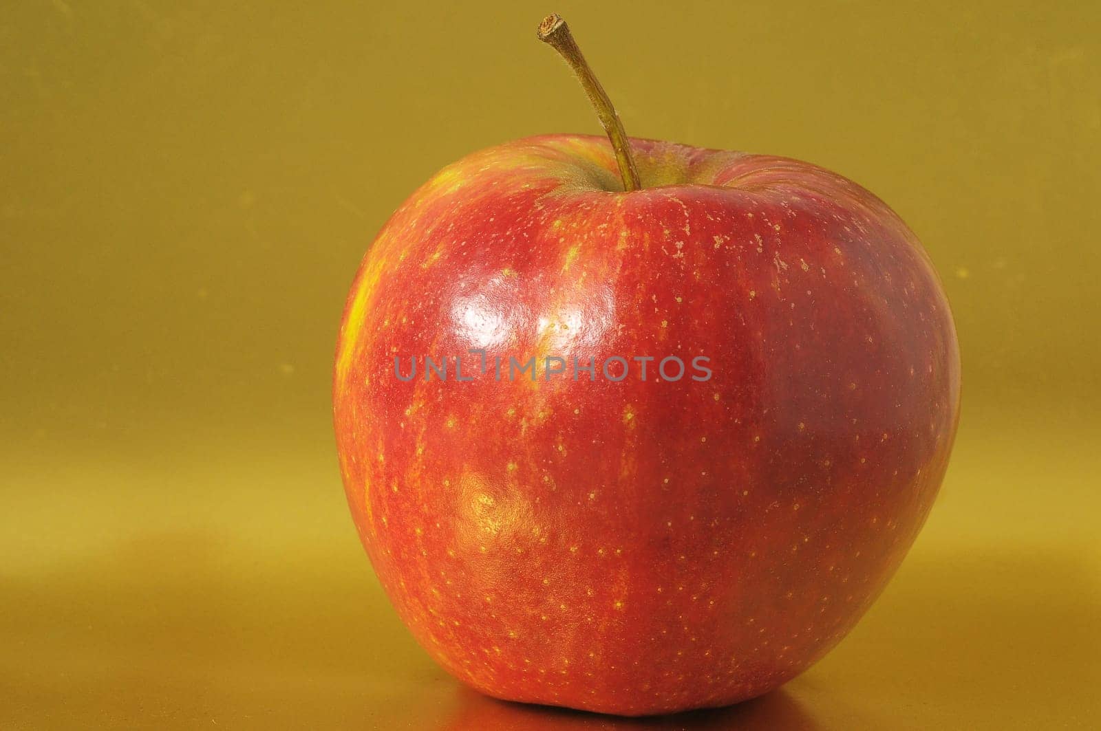 One Juicy Hot Red Apple over a Colored Background